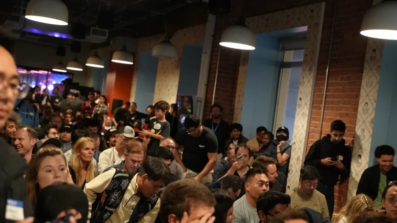 Packed crowd of several hundred attendees inside the ClawCon venue, with brick walls and pendant lights overhead